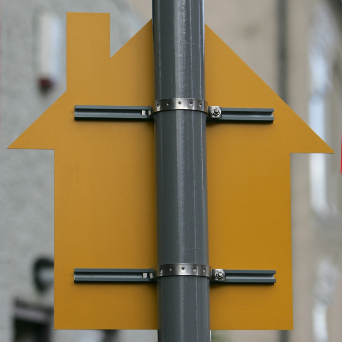 back view of a post mounted sign shaped like a house