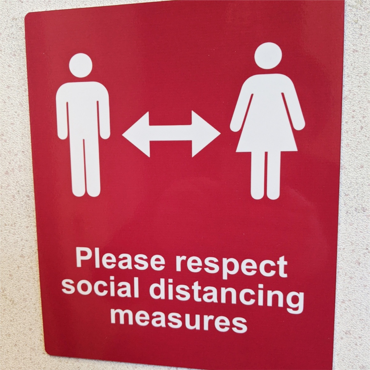 red sign informing people of social distancing measures in place